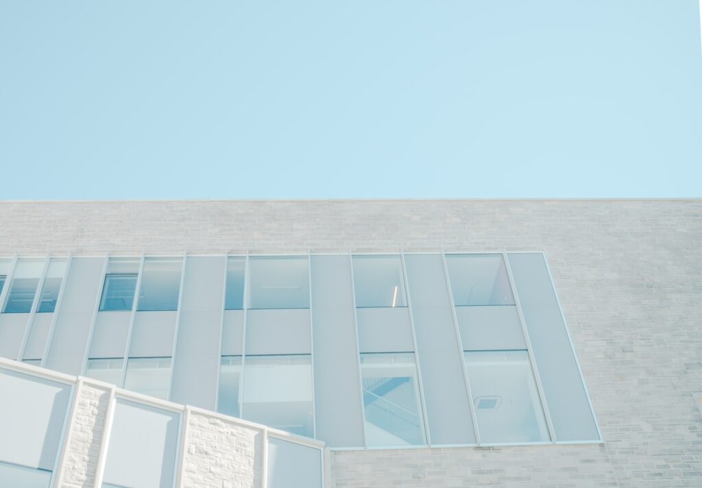 A White Building With Practical Solution Windows And A Blue Sky.
