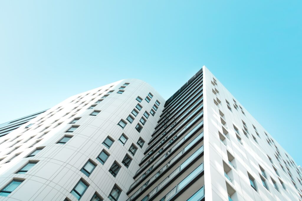 An Image Of A White Building With Reflective Window Film Against A Blue Sky.